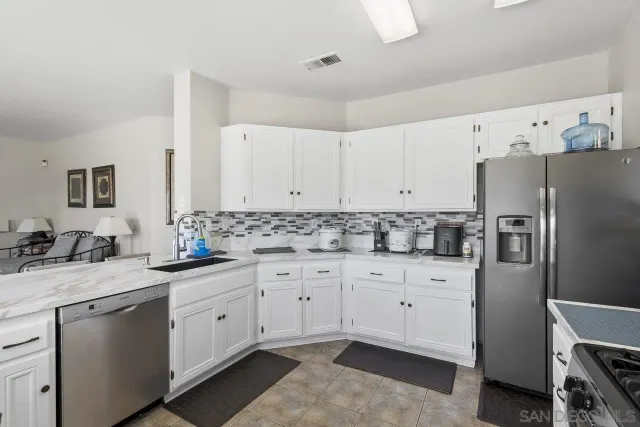 a kitchen with granite countertop white cabinets white stainless steel appliances and sink