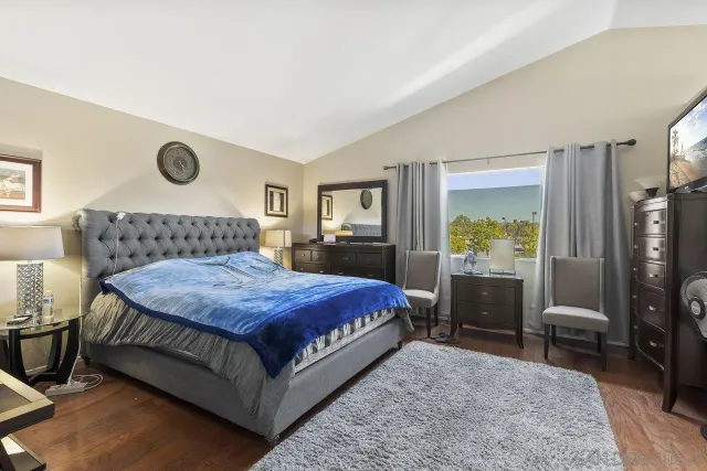 a bedroom with a bed and a flat tv screen on dresser