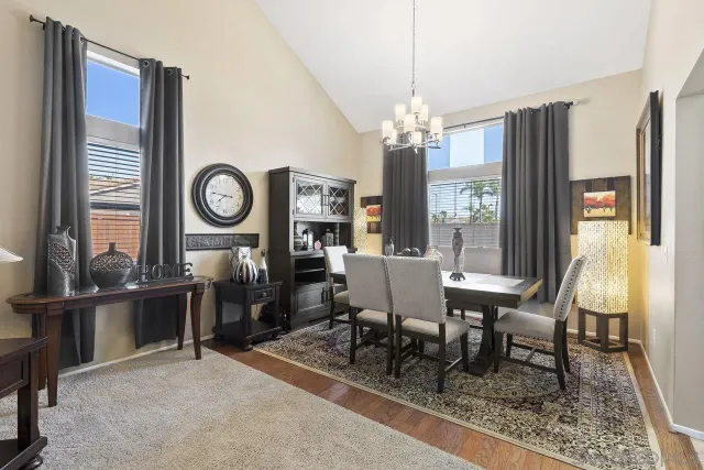 a dining room with wooden floor a chandelier a wooden table and chairs