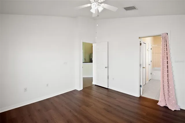 an empty room with wooden floor and a ceiling fan