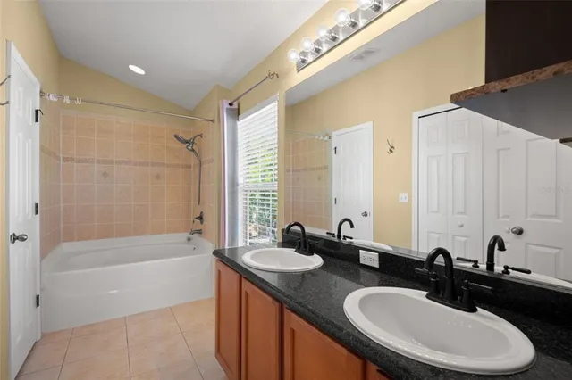 a bathroom with a double vanity sink and mirror with bathtub