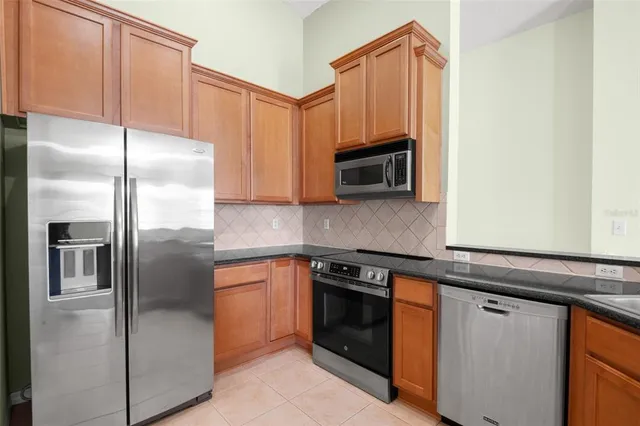 a kitchen with stainless steel appliances granite countertop a refrigerator a stove a sink and dishwasher