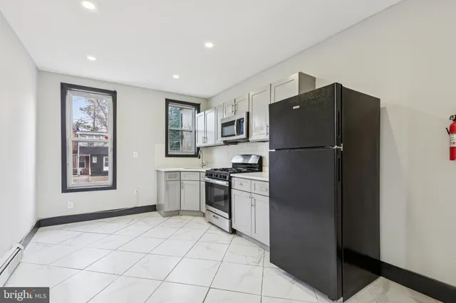 a kitchen with a refrigerator a stove top oven and cabinets