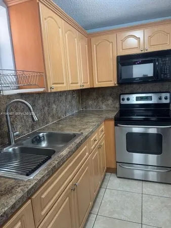 a kitchen with granite countertop a stove sink and cabinets