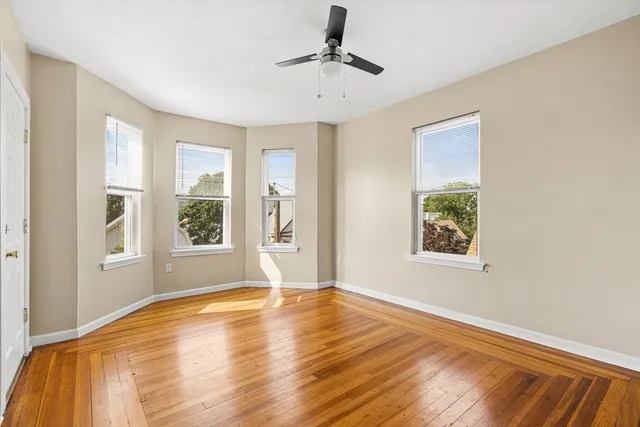 a view of empty room with a window and wooden floor