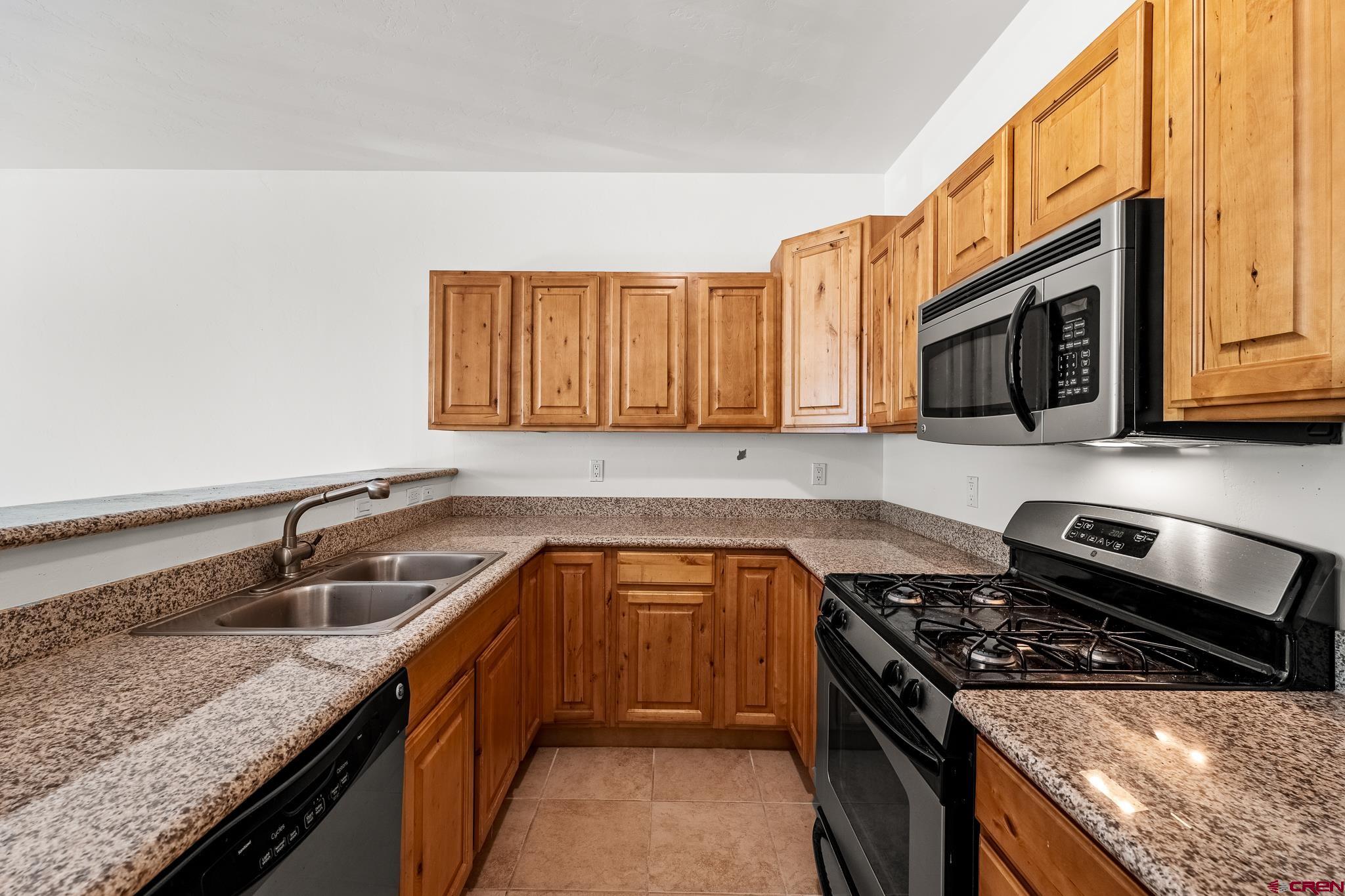 33 Cedar Ridge Way, Unit 3 Durango, CO 81301 - Photo 10 of 31 a kitchen with granite countertop a sink dishwasher stove and oven with wooden cabinets