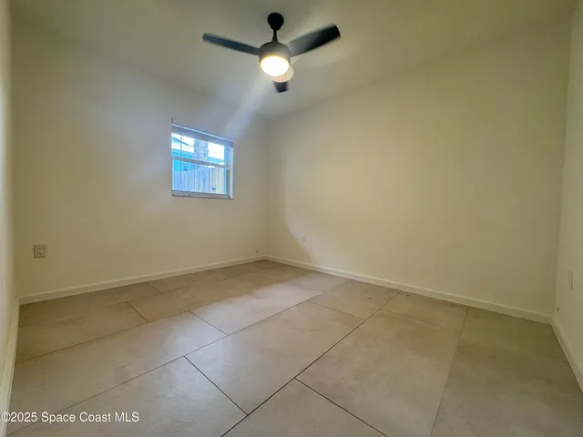 en empty room with ceiling fan and window
