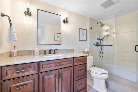 a bathroom with a granite countertop toilet sink shower and mirror