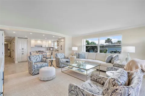 a kitchen with stainless steel appliances kitchen island granite countertop a dining table chairs and refrigerator