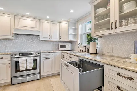 a kitchen with granite countertop a sink stainless steel appliances and a window