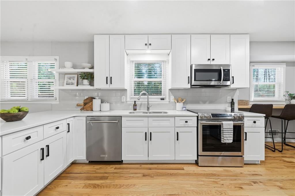 111 John Christopher Drive Alpharetta, GA 30009 - Photo 11 of 30 a kitchen with stainless steel appliances granite countertop a stove a sink dishwasher and a microwave oven with white cabinets
