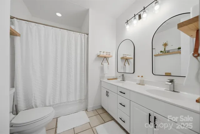 a spacious bathroom with a double vanity sink toilet and a mirror