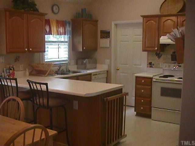 4831 Altha Street Raleigh, NC 27606 - Photo 2 of 9 a kitchen that has a sink a stove dining table and chairs