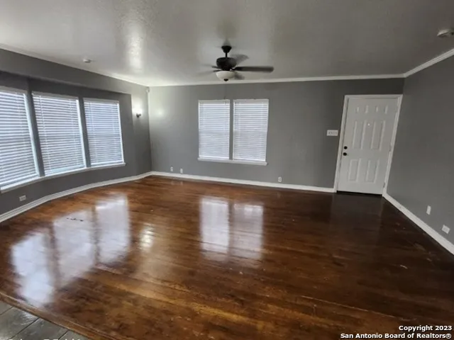 a view of an empty room with wooden floor and a window