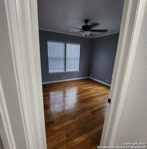 a view of an empty room with wooden floor and a window