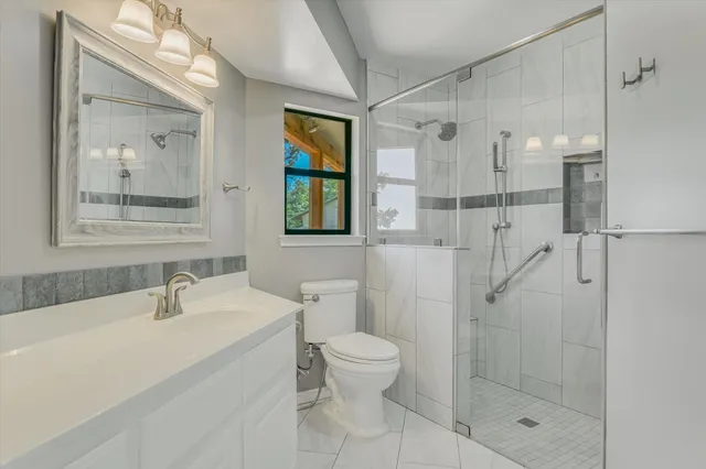 a bathroom with a shower sink mirror and toilet