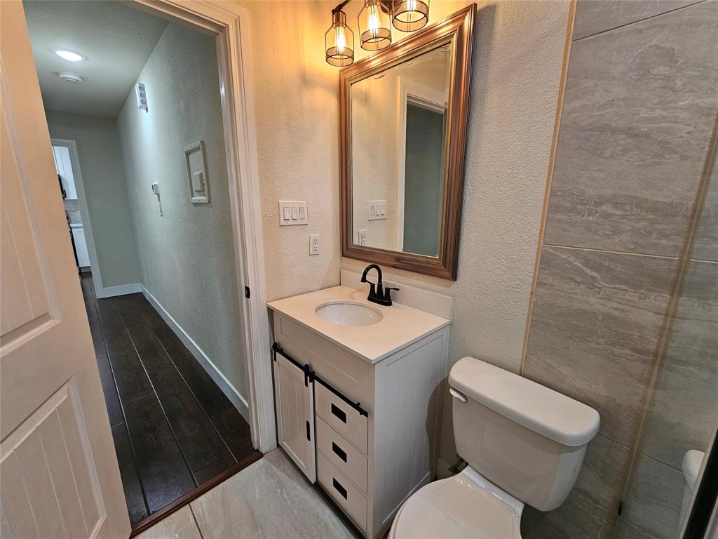 211 North Hampton Road Dallas, TX 75208 - Photo 17 of 22 Bathroom featuring a white vanity with a single basin, a framed mirror, and a three-light fixture
