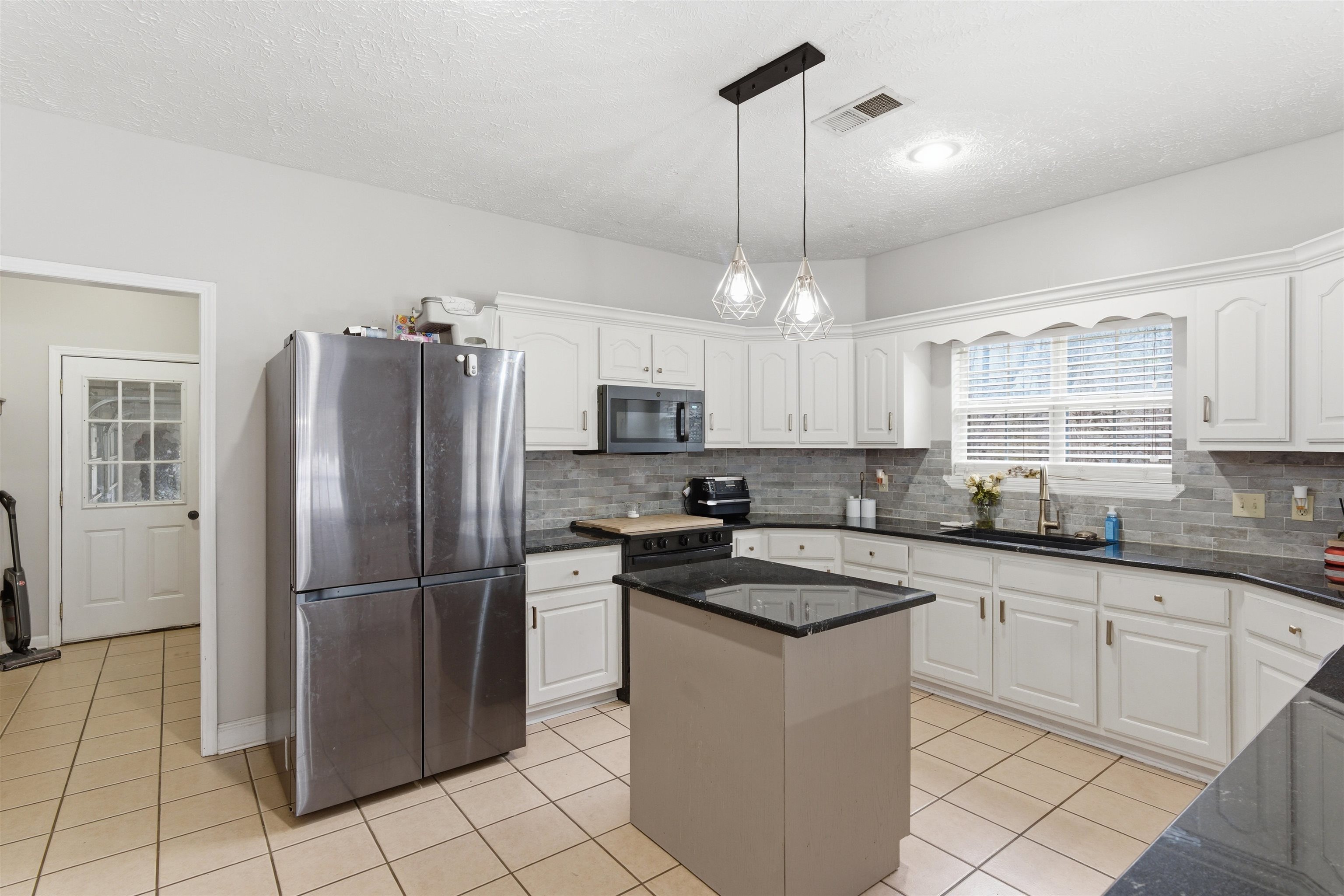 915 Cliffview Road Bolivar, TN 38008 - Photo 13 of 35 a kitchen with granite countertop a refrigerator a sink and white cabinets