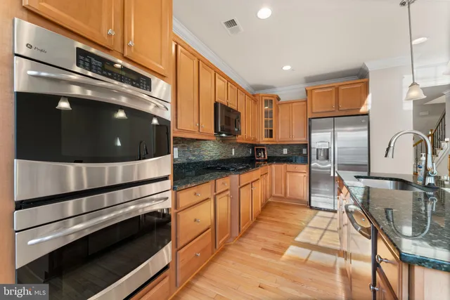 a kitchen with stainless steel appliances granite countertop a stove a sink and a refrigerator