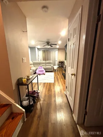 a hallway with a view of living room with wooden floor