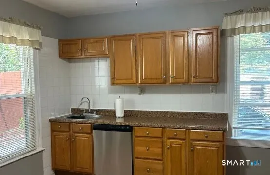 a kitchen with stainless steel appliances granite countertop white cabinets and a window