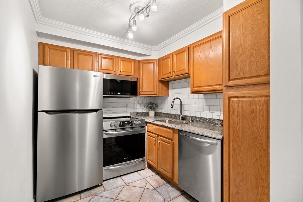 47 Will Drive, Unit 105 Canton, MA 02021 - Photo 5 of 13 a kitchen with stainless steel appliances granite countertop a refrigerator stove a sink dishwasher and microwave