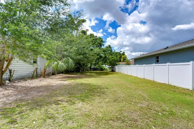 a view of a yard in front of a house with large trees
