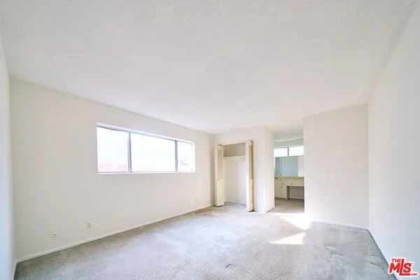 an empty room with windows and cabinet