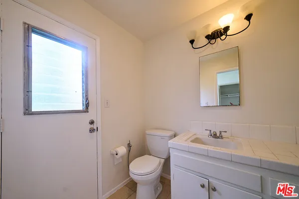 a bathroom with a toilet a sink a mirror and a window