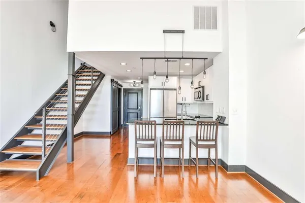 a kitchen with stainless steel appliances granite countertop a stove top oven a refrigerator a sink and a dining table with wooden floor