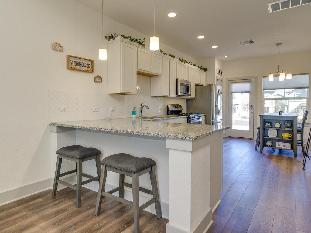 2257 Local Rebel Loop Leander, TX 78641 - Photo 9 of 26 a kitchen with stainless steel appliances granite countertop a stove top oven a sink a dining table and chairs with wooden floor