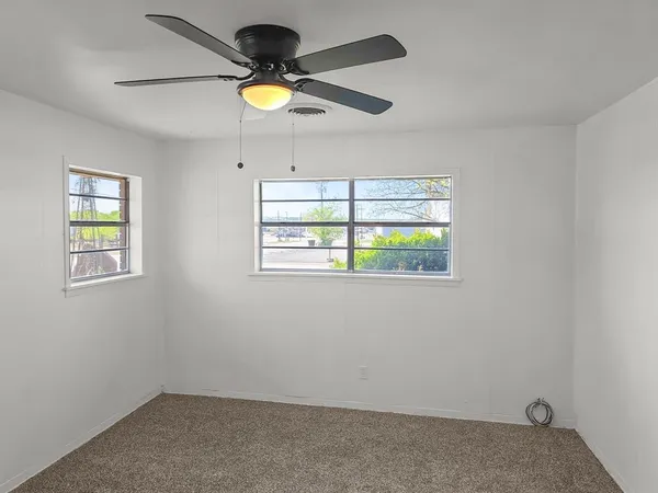 an empty room with windows and ceiling fan