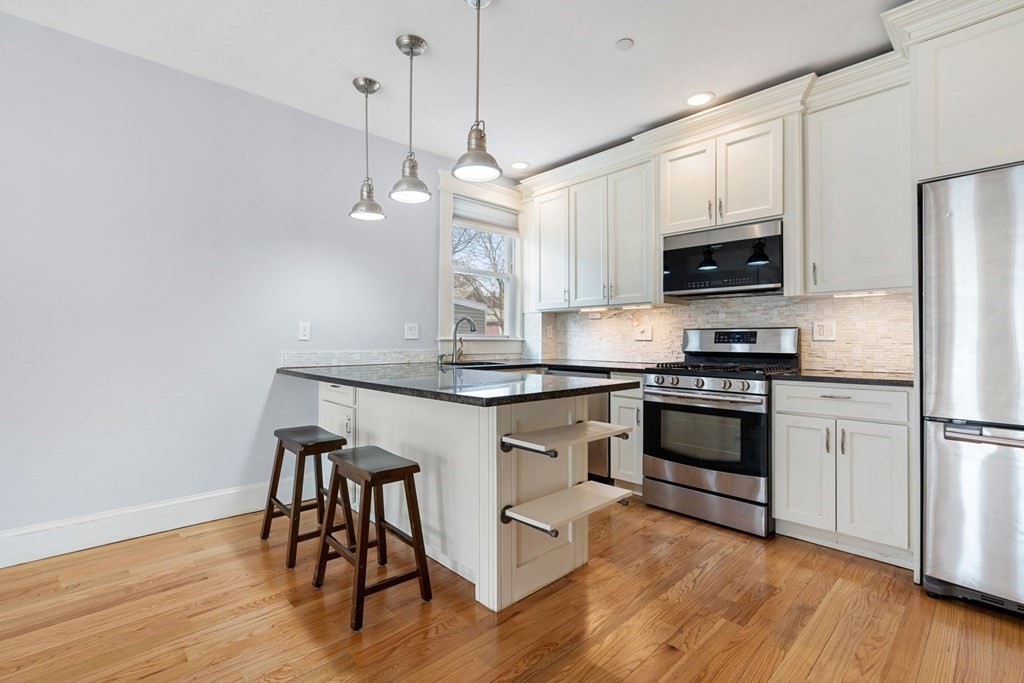 a kitchen with kitchen island white cabinets stainless steel appliances and wooden floor