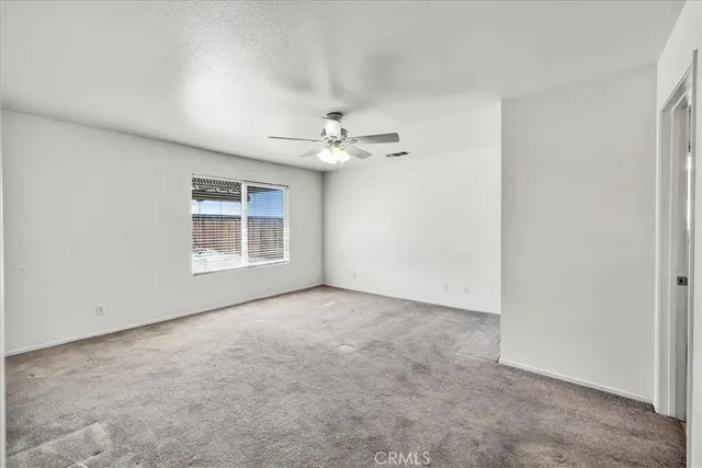 an empty room with windows and ceiling fan