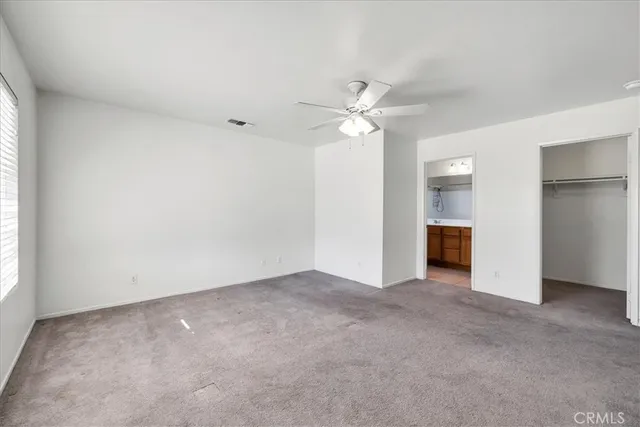 an empty room with chandelier fan and windows
