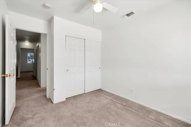 an empty room with closet and a chandelier fan