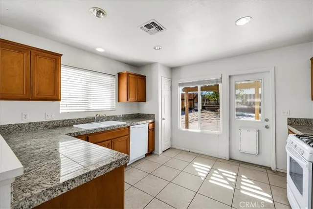 a kitchen with granite countertop a sink stove and refrigerator