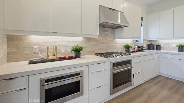 a kitchen with stainless steel appliances white cabinets and a stove top oven