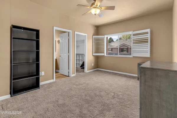 an empty room with chandelier fan and windows
