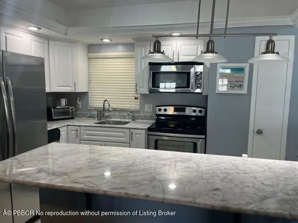 a kitchen with stainless steel appliances granite countertop a sink a stove top oven a refrigerator and a dishwasher