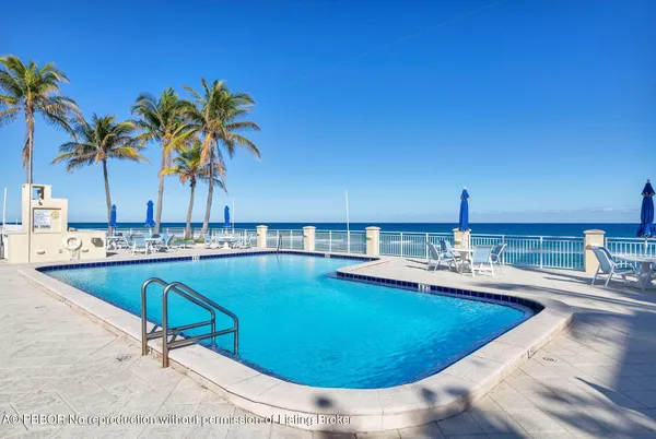 a view of a swimming pool with a lounge chair and palm trees