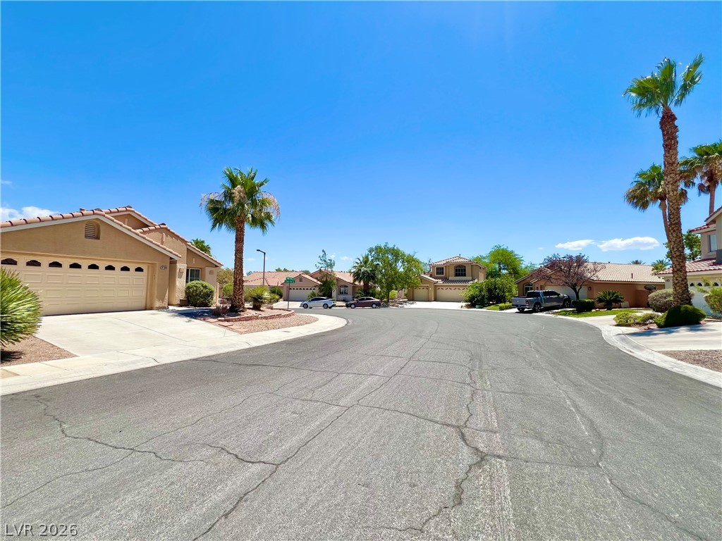 9708 Ridge Creek Place Las Vegas, NV 89134 - Photo 34 of 34 An inviting street scene unfolds with a collection of charming homes, lush landscaping, and vibrant palm trees.