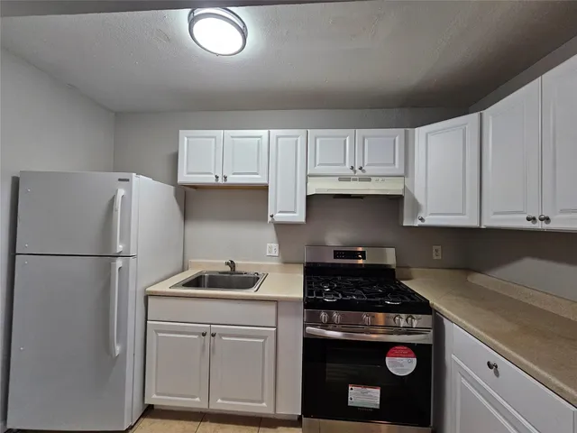 a kitchen with a refrigerator stove and white cabinets