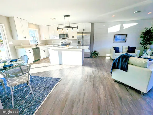 a large living room with kitchen island stainless steel appliances furniture a large window and a rug