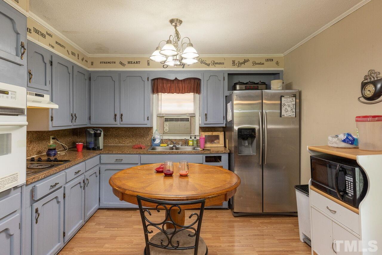 680 Haywood Bailey Road Roxboro, NC 27574 - Photo 10 of 29 a kitchen with stainless steel appliances a sink a stove a refrigerator cabinets and wooden floor