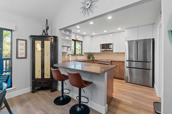 a kitchen with stainless steel appliances granite countertop a refrigerator a stove a sink dishwasher and a refrigerator with wooden floor