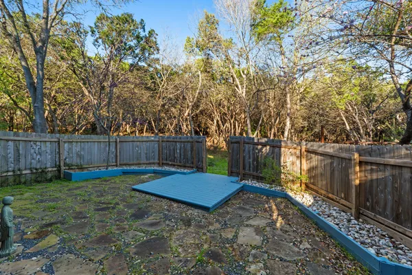 a view of a backyard with wooden fence and a large tree