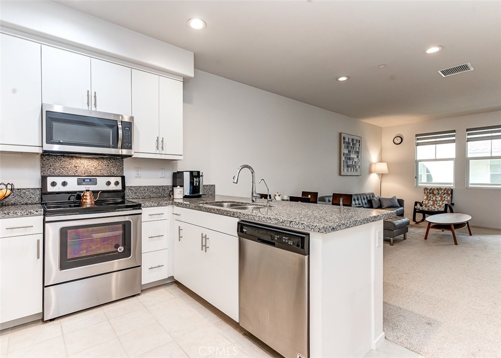 5756 Spring Street Buena Park, CA 90621 - Photo 3 of 16 a kitchen with stainless steel appliances granite countertop a stove top oven a sink dishwasher and white cabinets with wooden floor