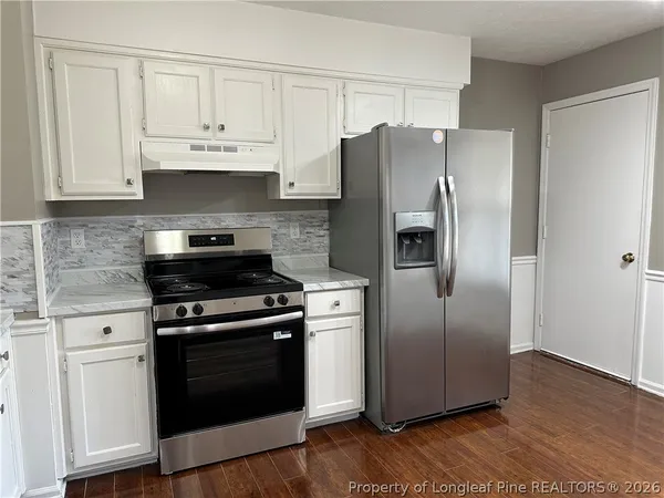a kitchen with stainless steel appliances granite countertop a refrigerator stove and white cabinets