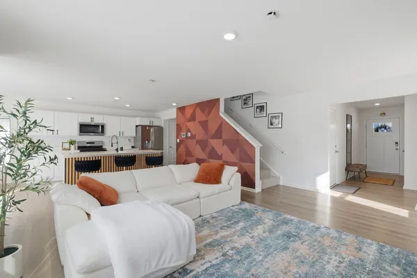 a kitchen with stainless steel appliances kitchen island granite countertop a refrigerator a stove a sink a dining table and chairs with wooden floor